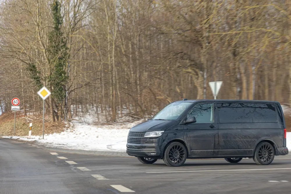 Black passenger van driving on a road.