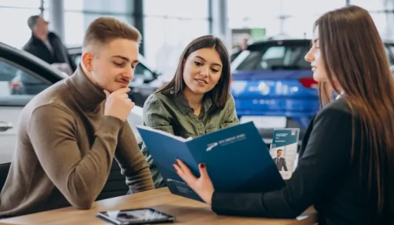 a couple looking over loan terms with an auto financing agent to get pre-approved for a car loan before purchasing a vehicle.