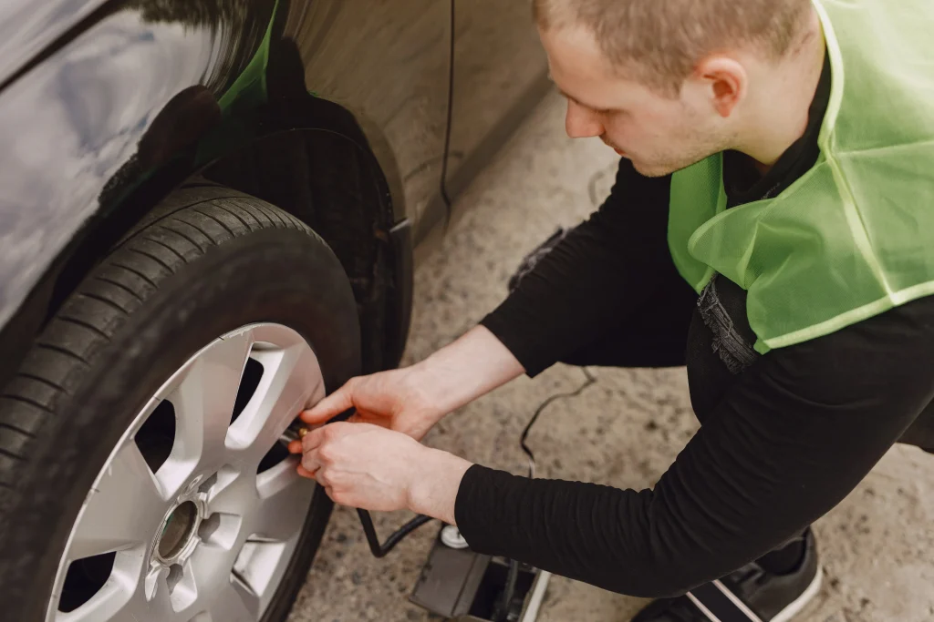 Driver preparing to remove the wheel cover and loosen lug nuts while learning how to change a car tire.