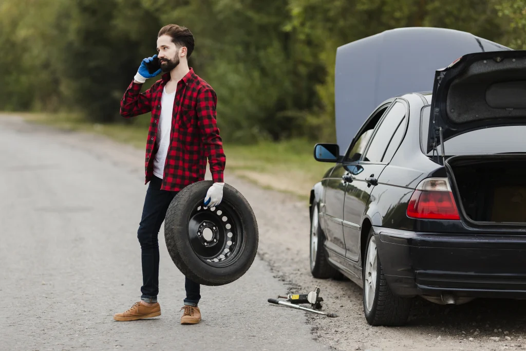 Driver calling roadside assistance for help instead of attempting how to change a car tire.