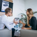 An insurance representative showing policy options on a tablet to a customer learning how to switch car insurance companies in Bangladesh