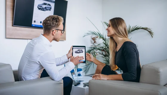 An insurance representative showing policy options on a tablet to a customer learning how to switch car insurance companies in Bangladesh