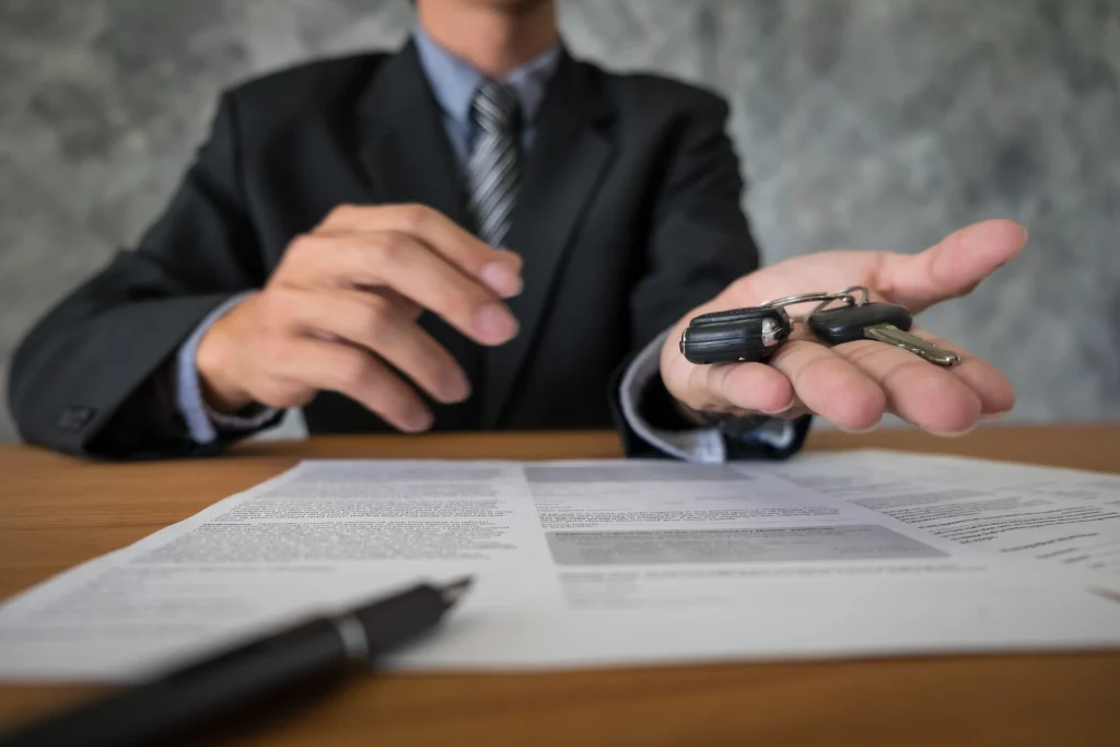 An agent handing over car keys over policy documents required for switching car insurance in Bangladesh