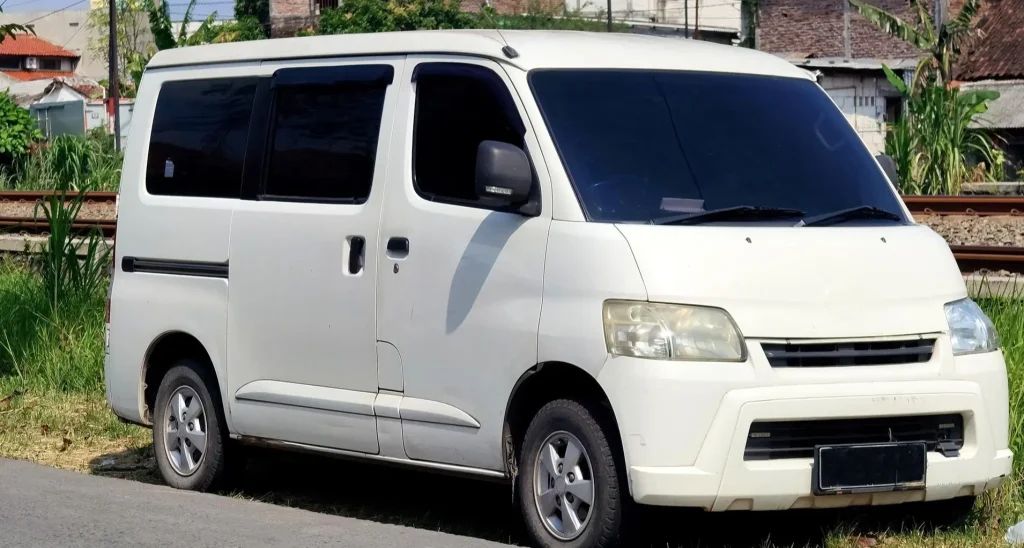 A small white passenger minivan parked outdoors